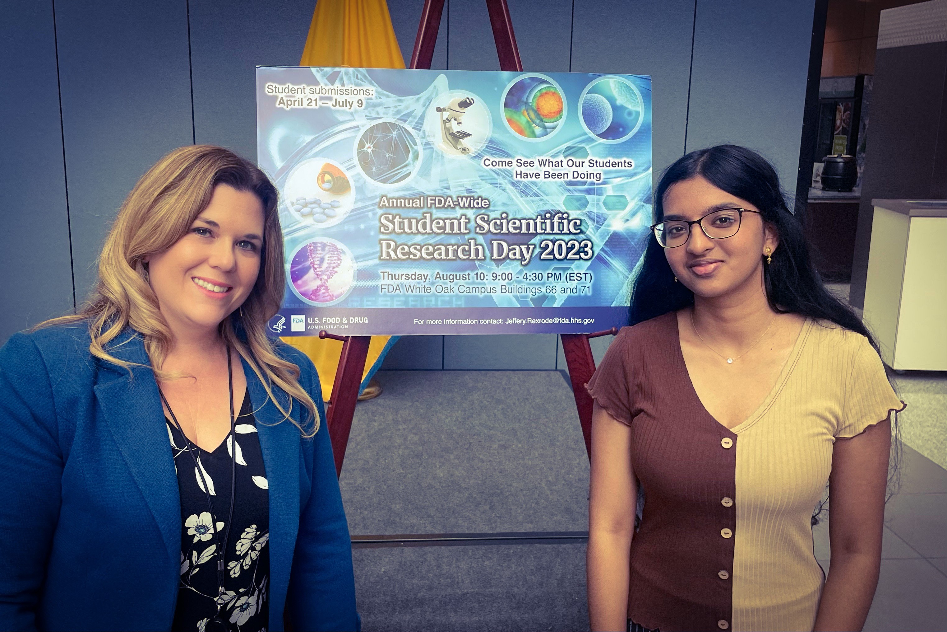 Risa Verma and her mentor Dr. Laura Markley in front of a poster for FDA Student Scientific Research Day 2023.