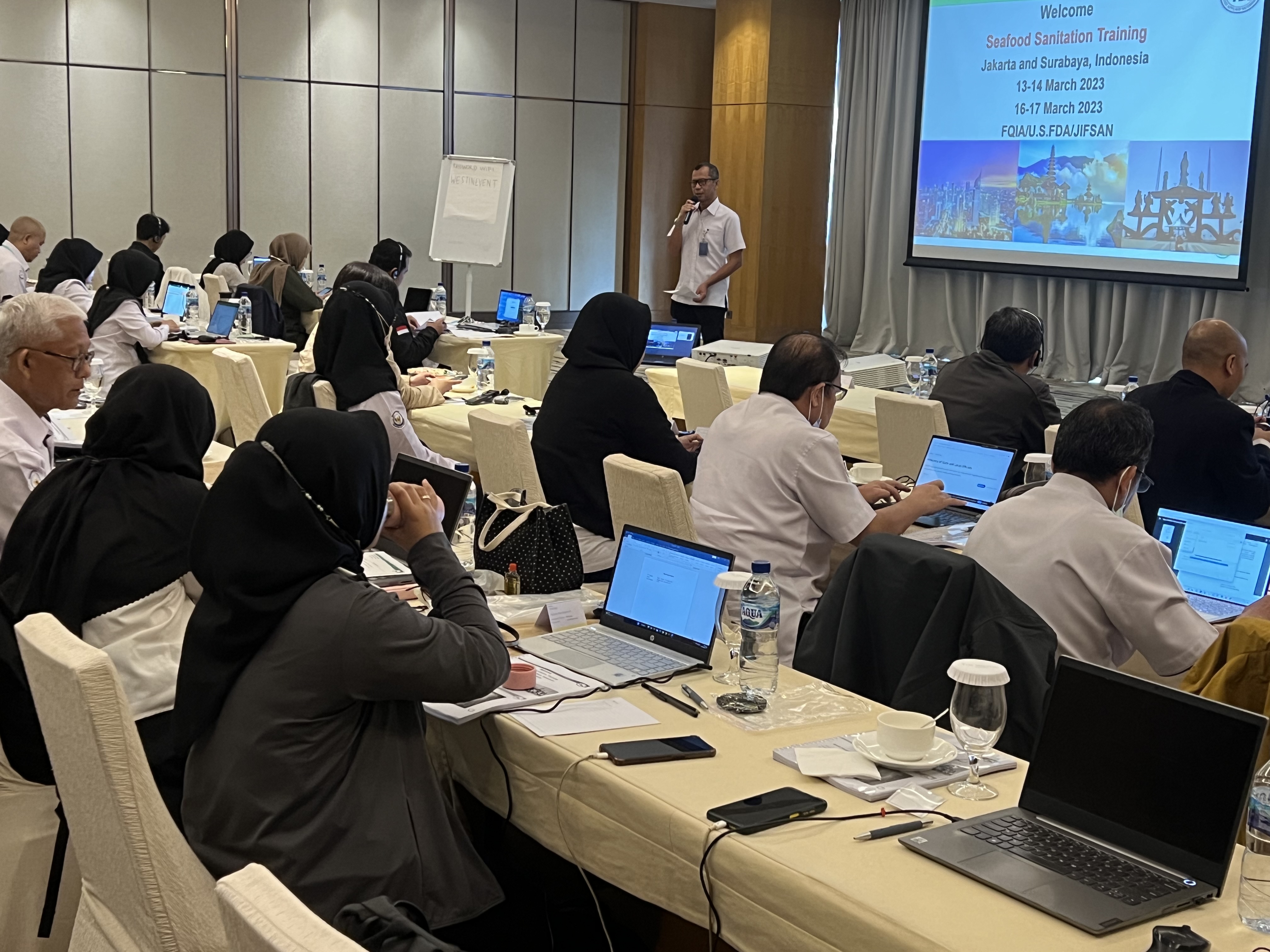 Indonesian conference participants sit in rows with laptop computers listening to the seafood sanitation training welcome lecture.