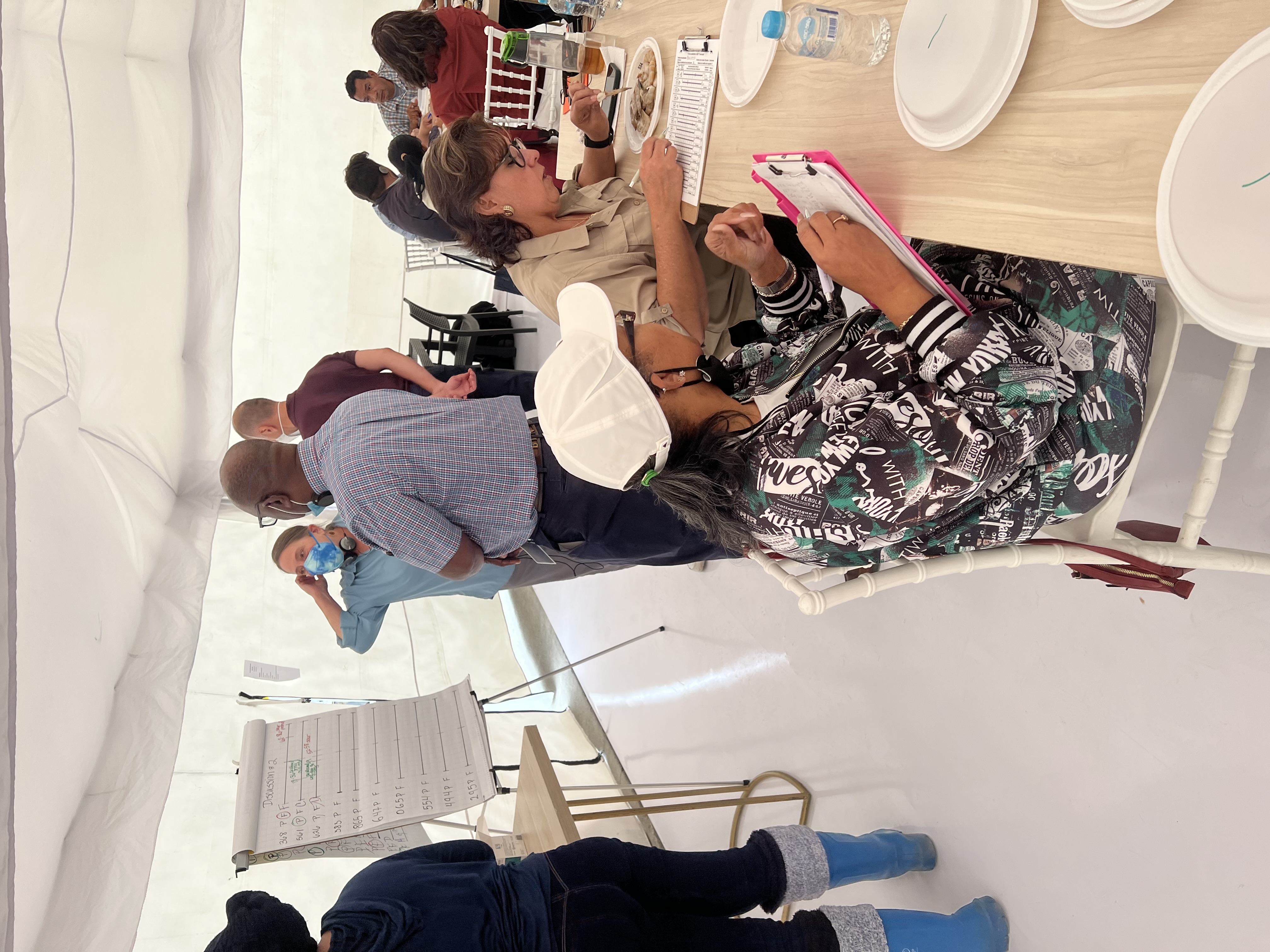 Paticipants in the sensory decomposition workshop are seen examining plates of shrimp, recording observations with a clipboard, and holding discussions.